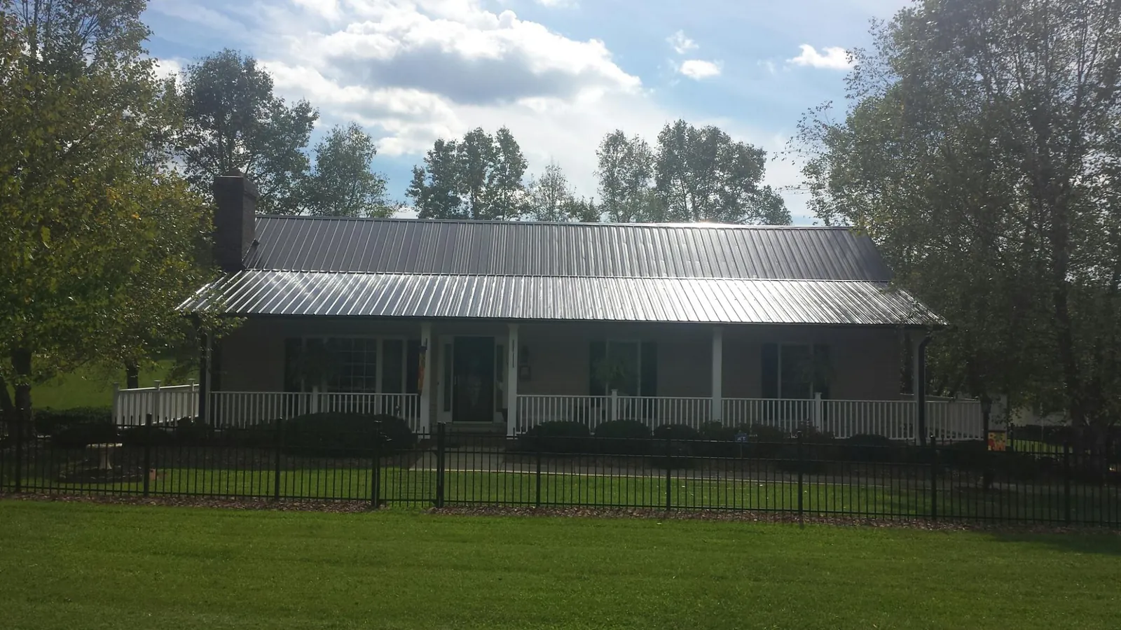 Gray metal roof on a brick ranch with a full width front porch — Gutter Guard Installation work by our crew in Monroe